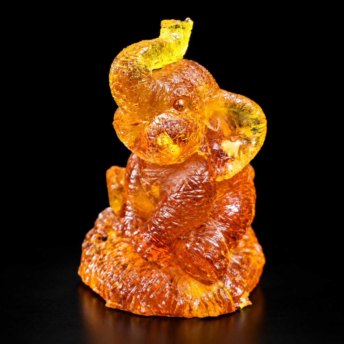 Made in USA Natural Baltic Amber seated elephant figurine, trunk up, honey amber good luck charm, black studio background — KIZIMA®