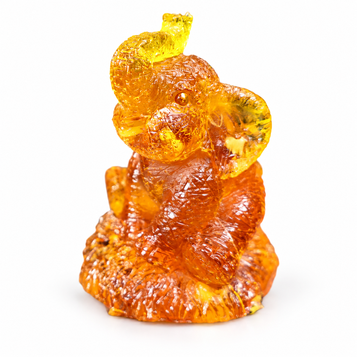 Natural Baltic Amber seated elephant figurine by KIZIMA®, white background, small lucky elephant with raised trunk