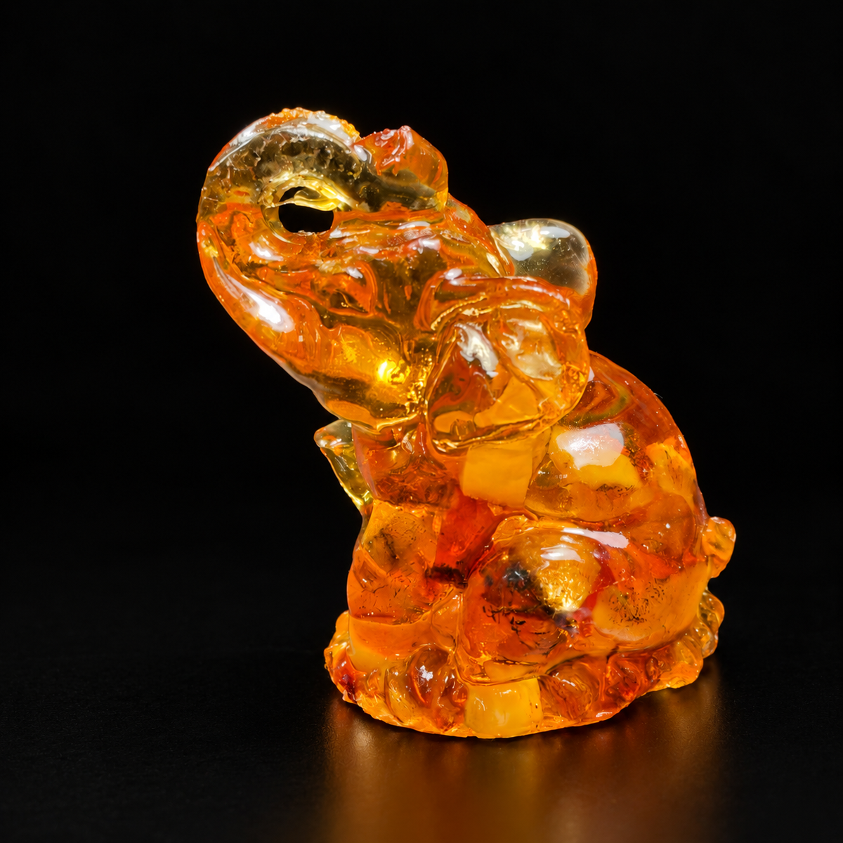 Made in USA Natural Baltic Amber seated elephant figurine, 5 cm, trunk raised, honey-cognac amber, black studio background — KIZIMA®