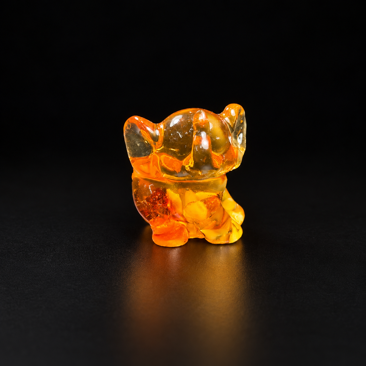 Made in USA Natural Baltic Amber baby elephant figurine, 4 cm, big-eared sitting calf, golden amber, black studio background — KIZIMA®