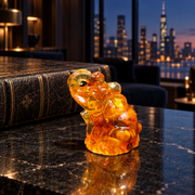 KIZIMA Baltic amber seated trunk-up elephant figurine, 6 cm, in a dark Manhattan luxury interior