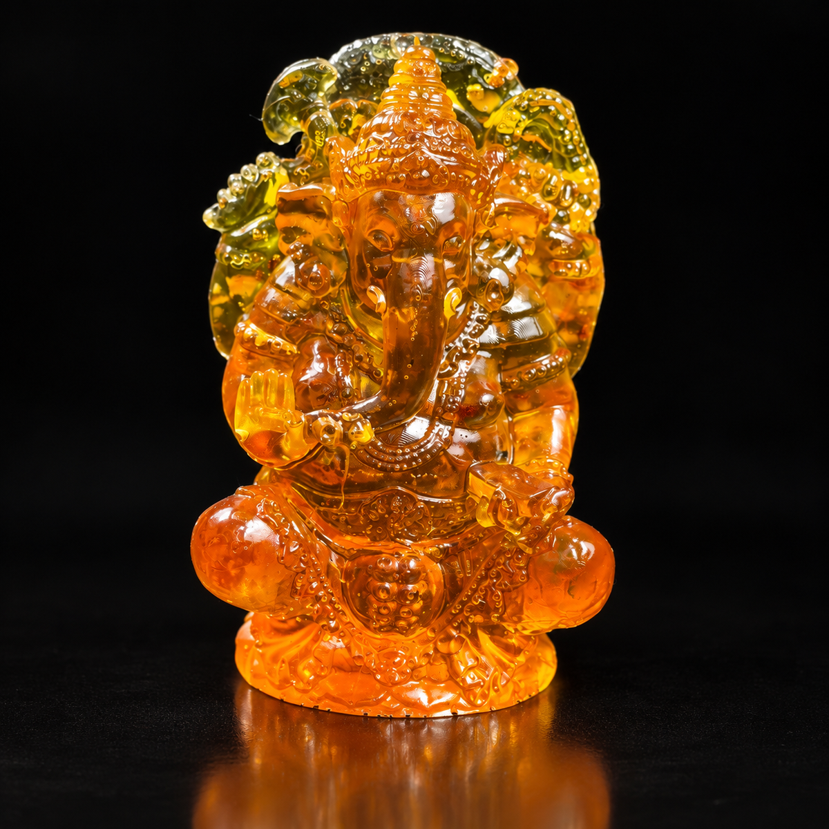Made in USA Natural Baltic Amber seated Ganesha statue, 8 cm, crowned elephant god with raised hand, honey-orange amber, black studio background — KIZIMA®