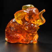 Made in USA Natural Baltic Amber mother and baby elephant figurine, hugging elephant pair in honey-cognac amber, black studio background — KIZIMA®