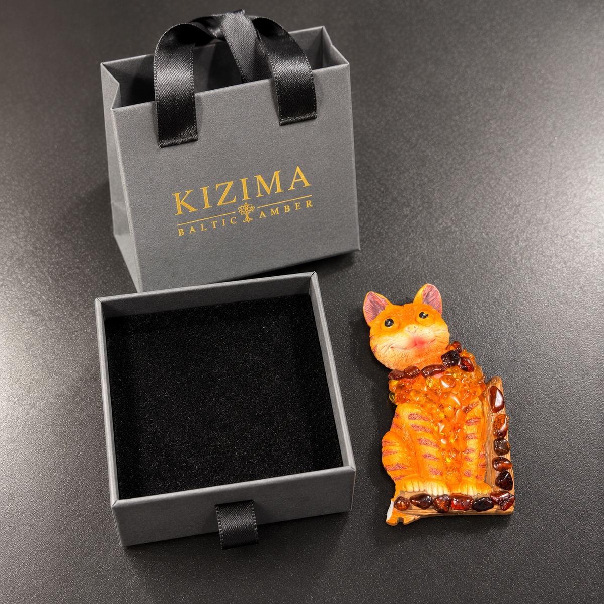 Made in USA Natural Baltic Amber cat fridge magnet by KIZIMA® beside the small gray KIZIMA® gift box and matching gift bag