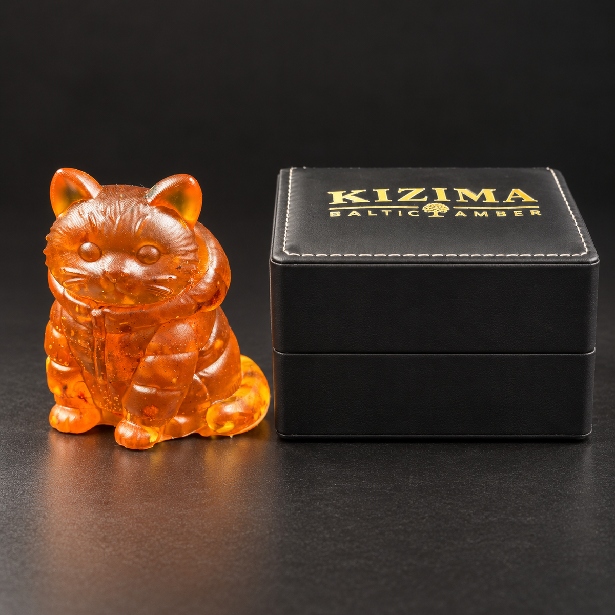 Made in USA Natural Baltic Amber hooded cat figurine by KIZIMA® beside the closed black KIZIMA® gift box