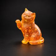 Made in USA Natural Baltic Amber raised-paw cat figurine by KIZIMA®, 7 cm golden sitting cat waving one paw, black studio background