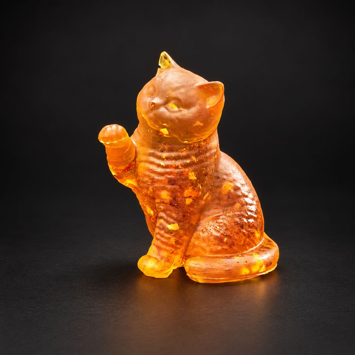 Made in USA Natural Baltic Amber raised-paw cat figurine by KIZIMA®, 7 cm golden sitting cat waving one paw, black studio background