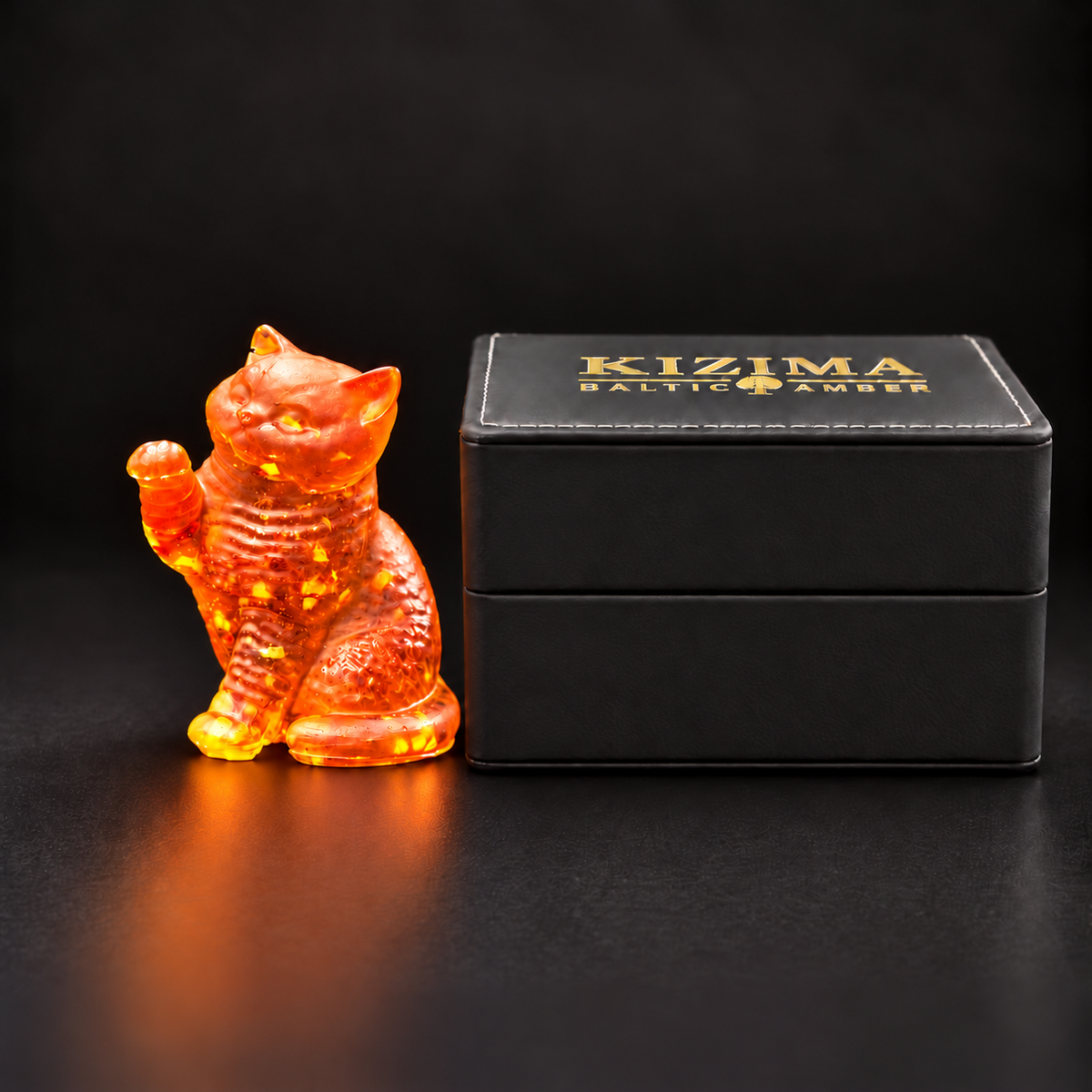 Made in USA Natural Baltic Amber raised-paw cat figurine by KIZIMA® beside the closed black KIZIMA® gift box