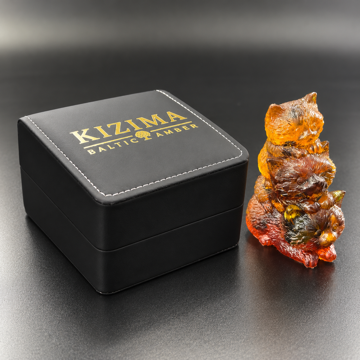 Made in USA Natural Baltic Amber stacked kitten family figurine by KIZIMA® beside the black stitched KIZIMA® gift box
