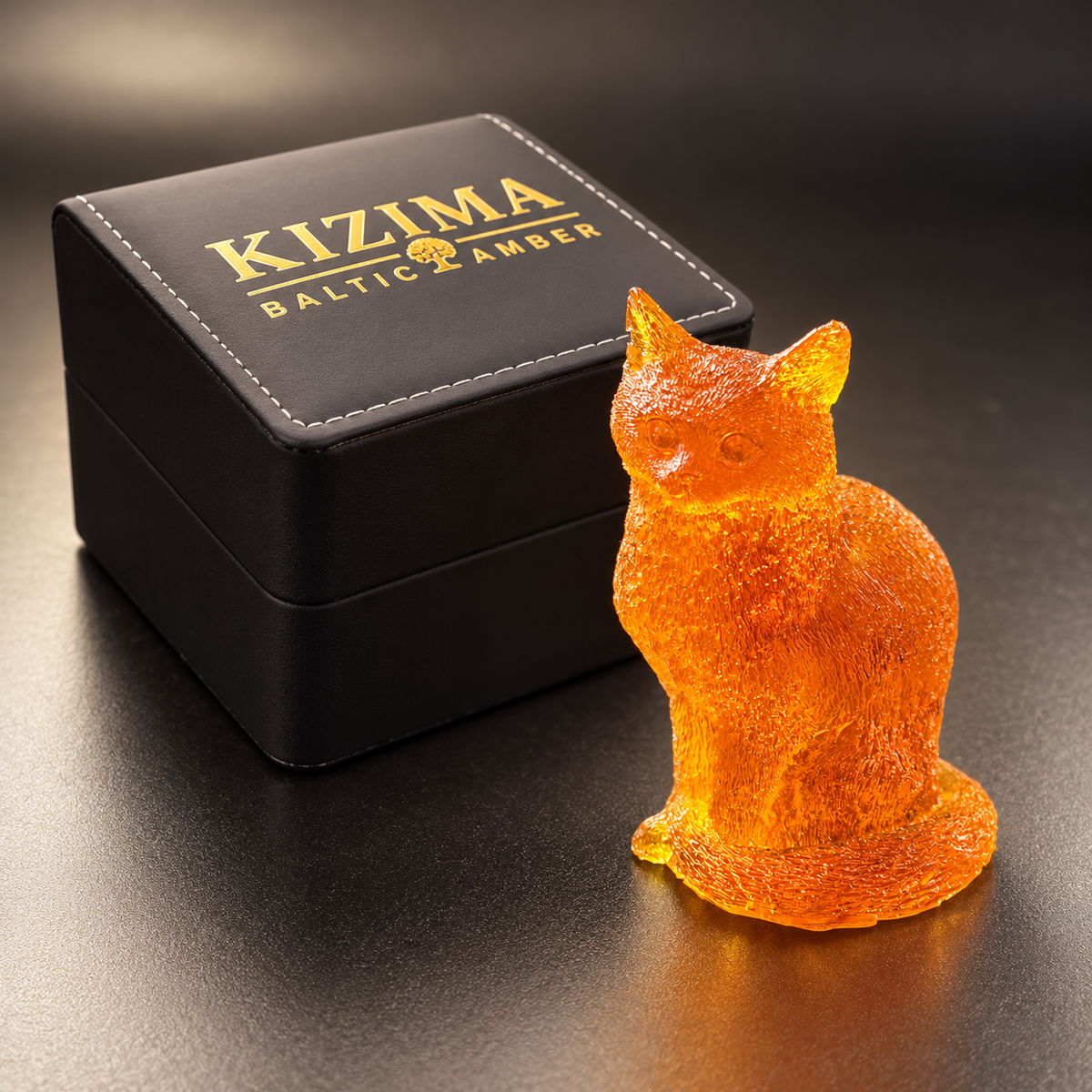 Made in USA Natural Baltic Amber textured cat figurine by KIZIMA® beside the black KIZIMA® gift box with gold branding