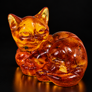 KIZIMA amber lying cat figurine on a black studio background