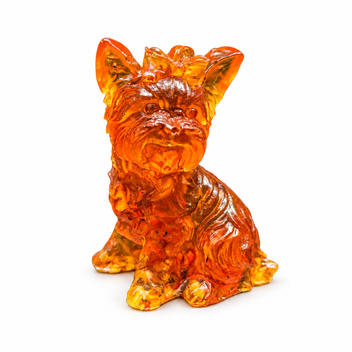 Seated amber Yorkshire Terrier on white, showing the bow on its head, long carved coat and small tail peeking out behind its haunch.