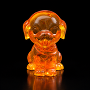 Front view of a round-headed amber cartoon puppy, with floppy ears and its tongue out, reflected on a black surface.