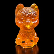 Front view of an amber fluffy puppy with upright rounded ears, a textured head, collar and tongue showing, on reflective black.