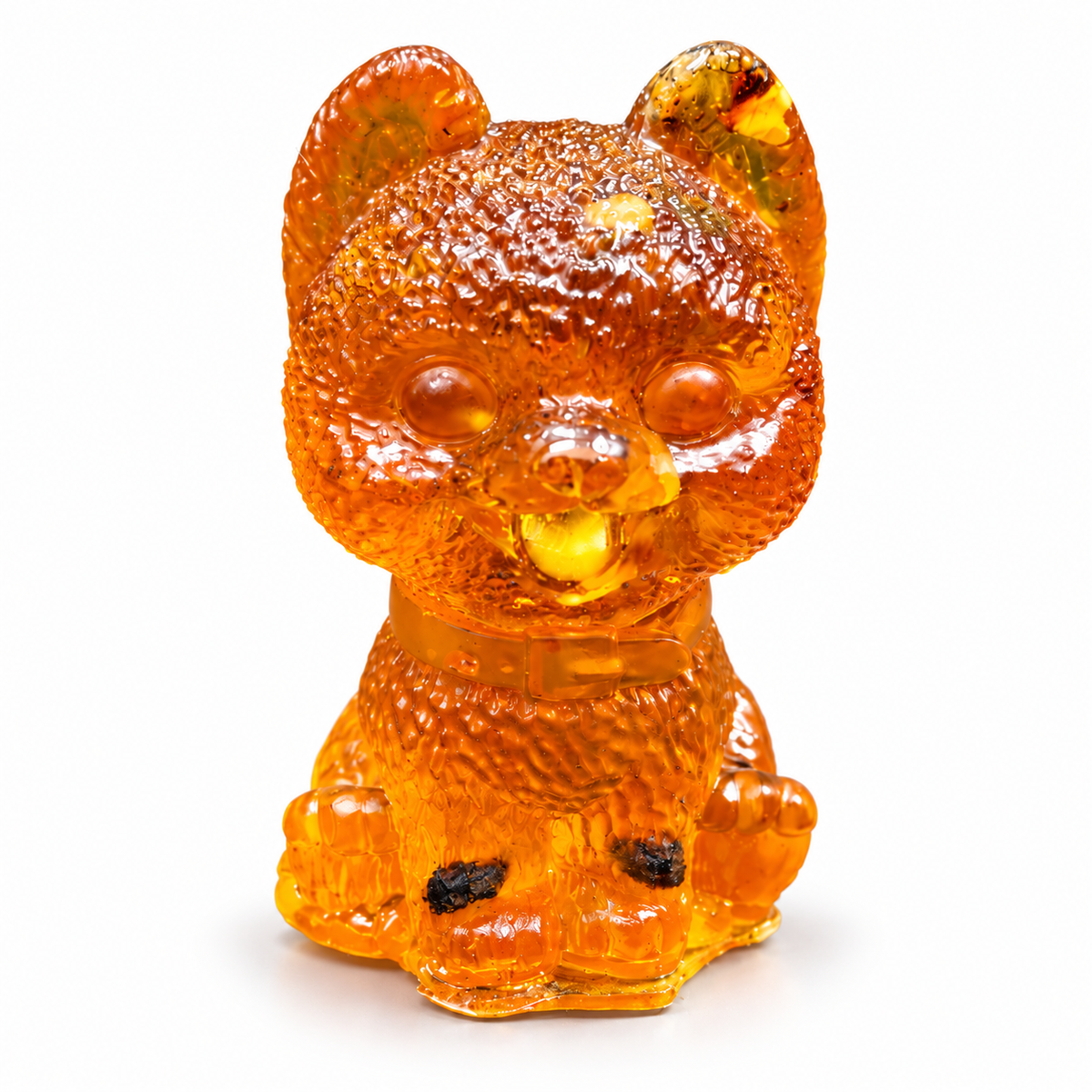 Front-facing fluffy puppy figurine on white, with textured amber fur, a small collar and dark inclusions near its rounded paws.