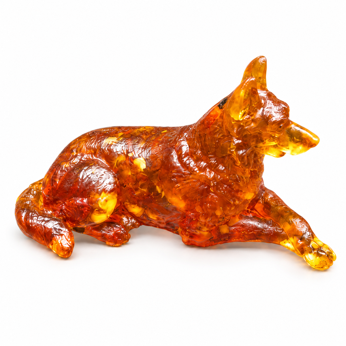 Reclining German Shepherd figurine on white, with a raised muzzle, crossed front paws and a tail curled beside its amber body.