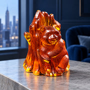 Golden cognac amber bear embracing a tree on a gray stone console, contrasting with a navy blue room and softly blurred Manhattan skyline.