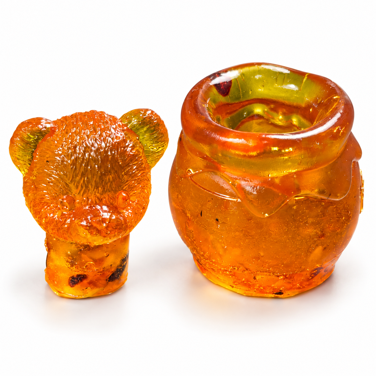 Open golden amber honey jar beside its removable bear head lid, showing the hollow interior on a white background.