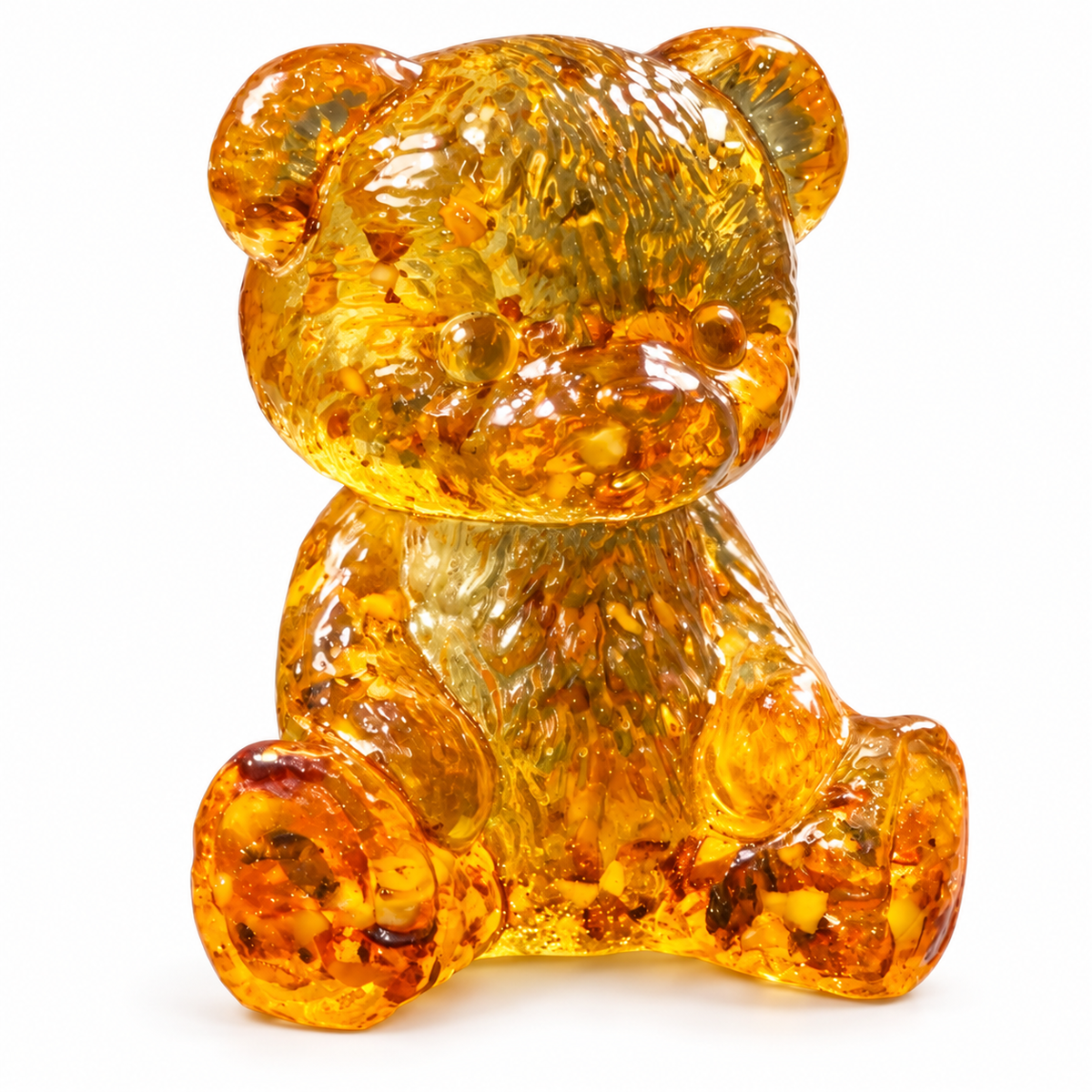 Golden amber teddy bear seated on a white background, showing rounded paws, carved fur and translucent amber fragments.
