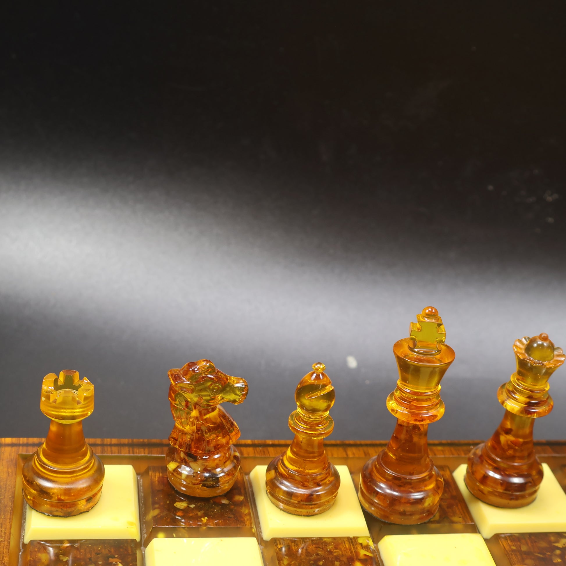 Made in USA natural Baltic amber chess set on rattan-inlaid wood board, honey and cognac amber chess pieces close up, KIZIMA