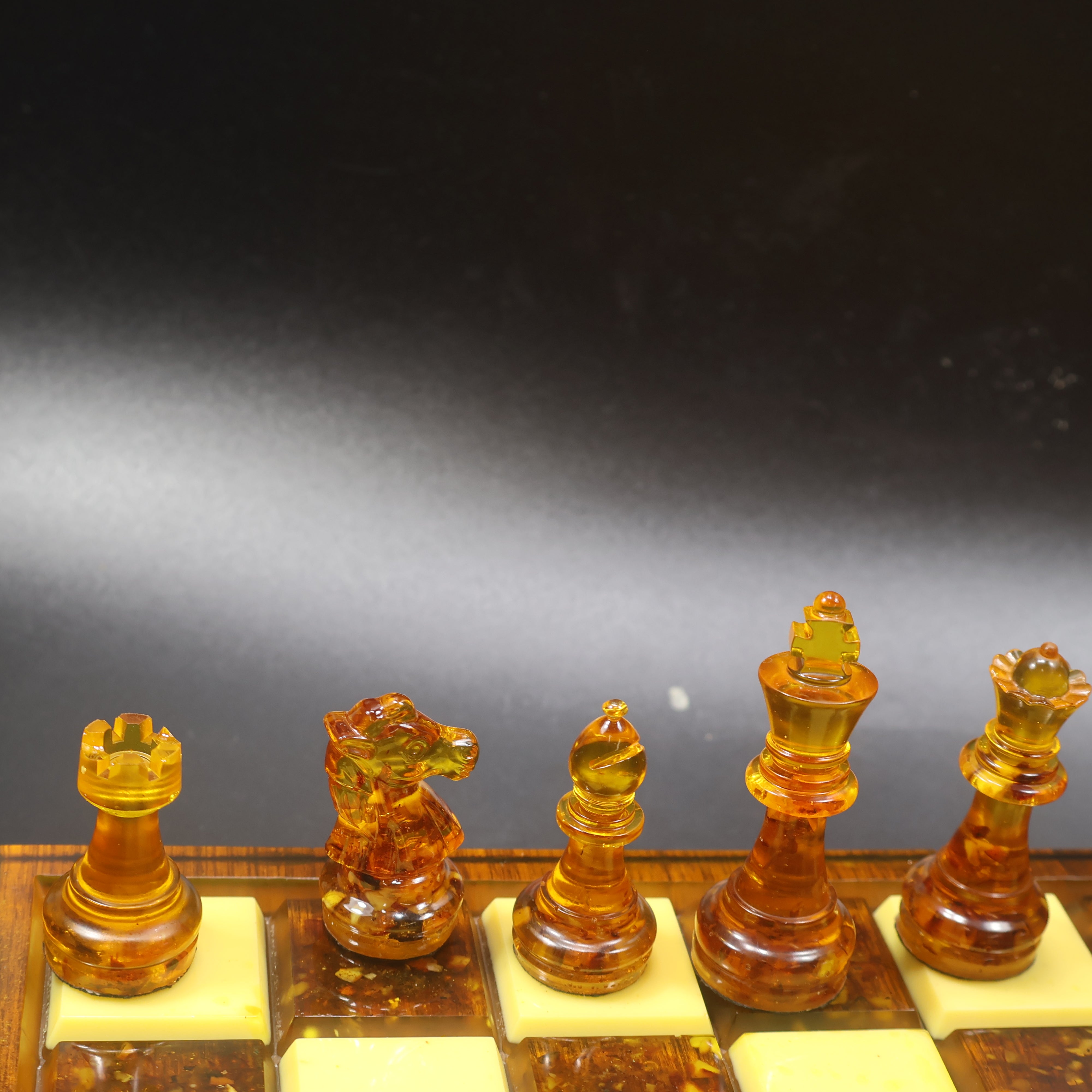 Made in USA natural Baltic amber chess set on rattan-inlaid wood board, honey and cognac amber chess pieces close up, KIZIMA