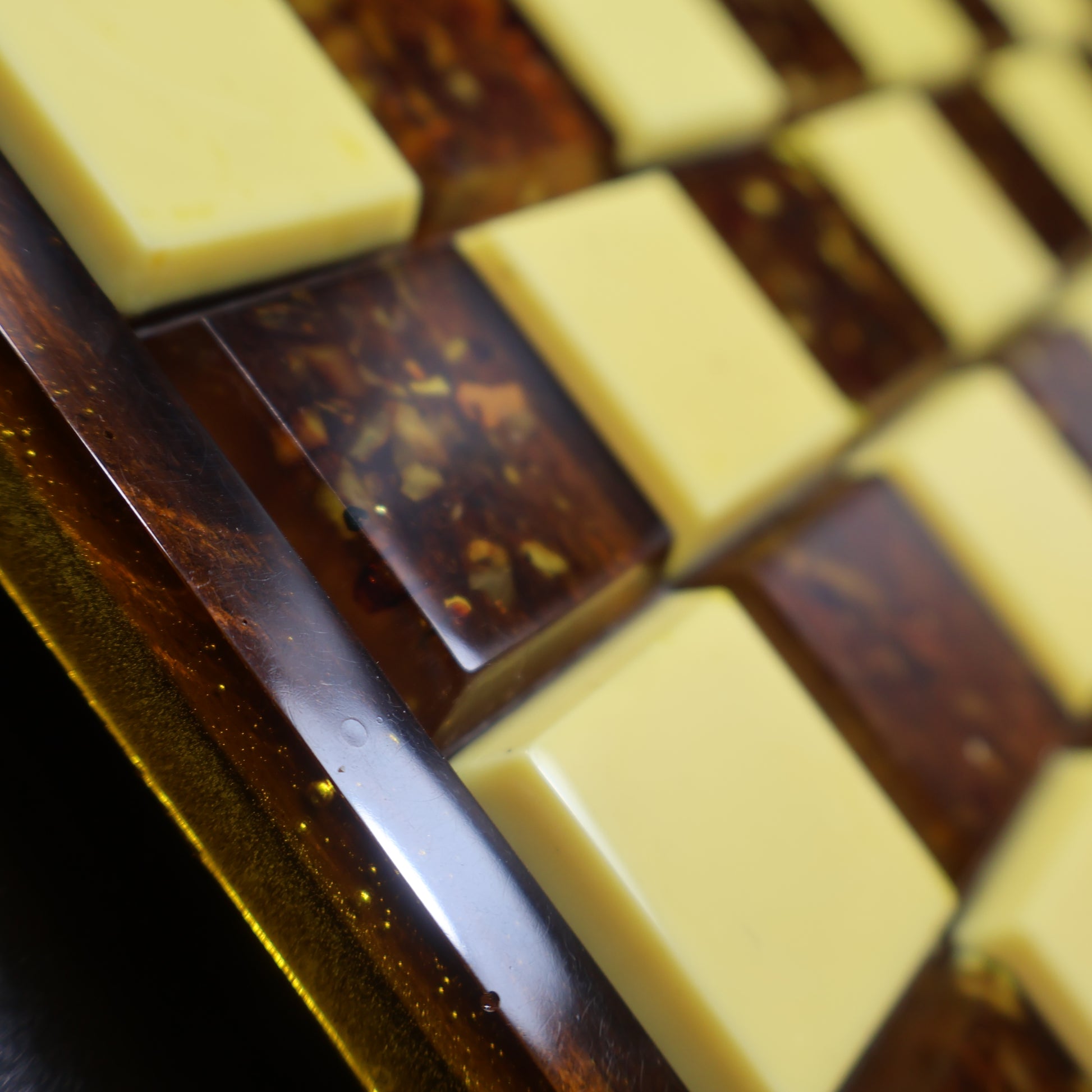 Close up of rattan-inlaid wood chess board corner with genuine Baltic amber squares, natural rattan chess board detail KIZIMA