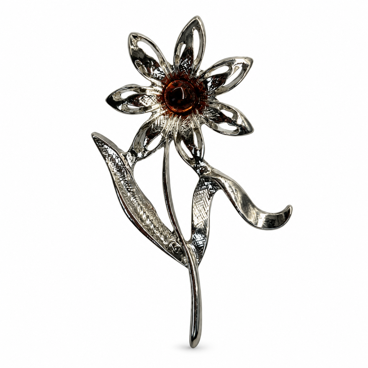 KIZIMA silver-tone seven-petal openwork daisy brooch with a dark cognac amber center and flowing leaves on white.