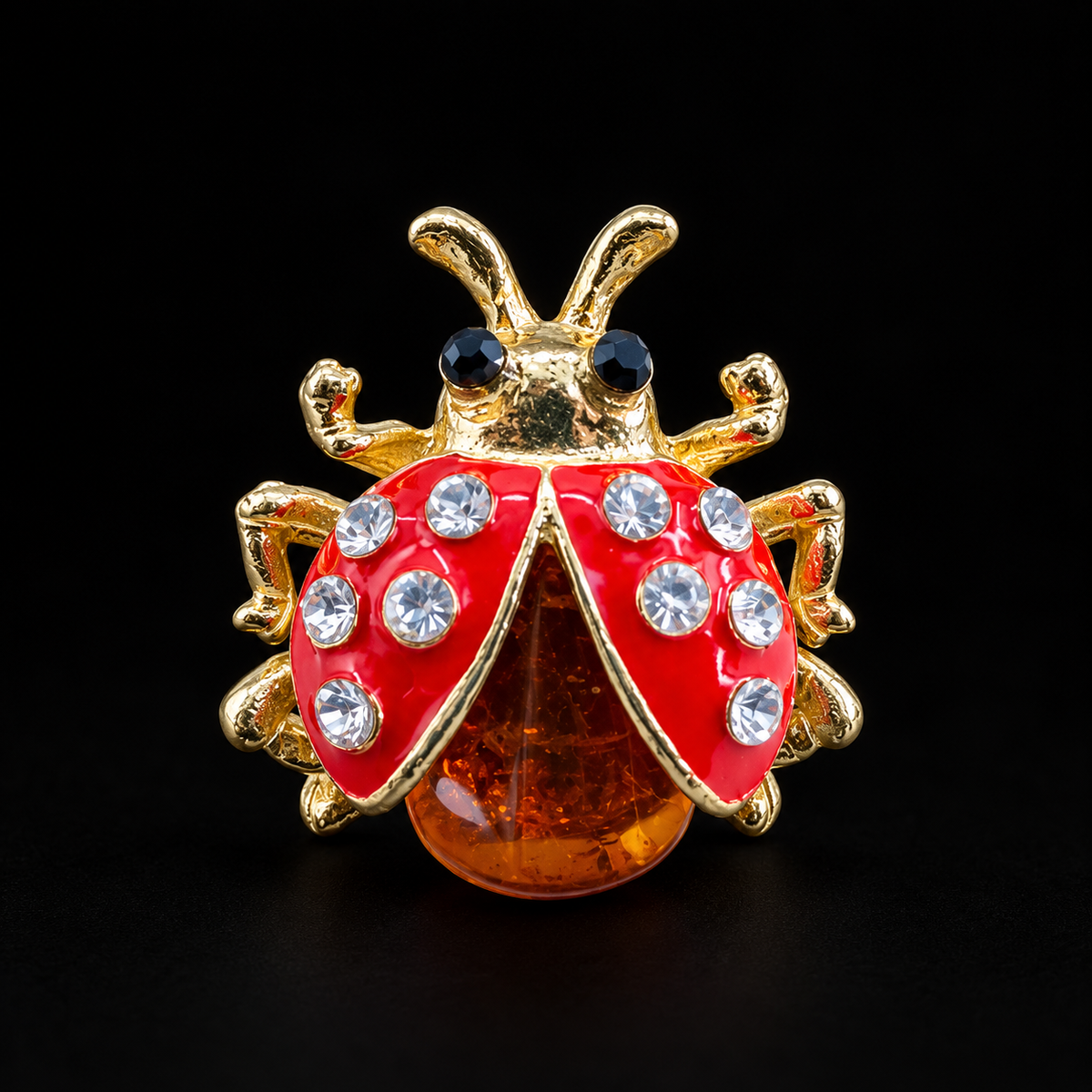 KIZIMA ladybug brooch 20N0180 with red enamel wings, clear crystals and cognac amber on a black background.