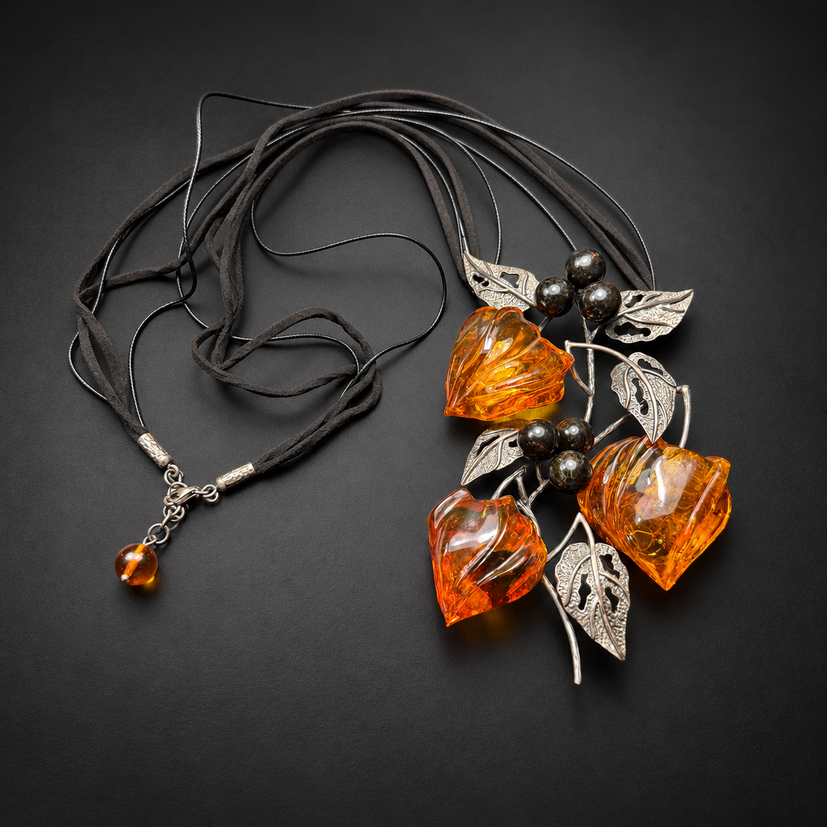 KIZIMA carved amber physalis necklace, full black-cord layout on charcoal, studio view 1