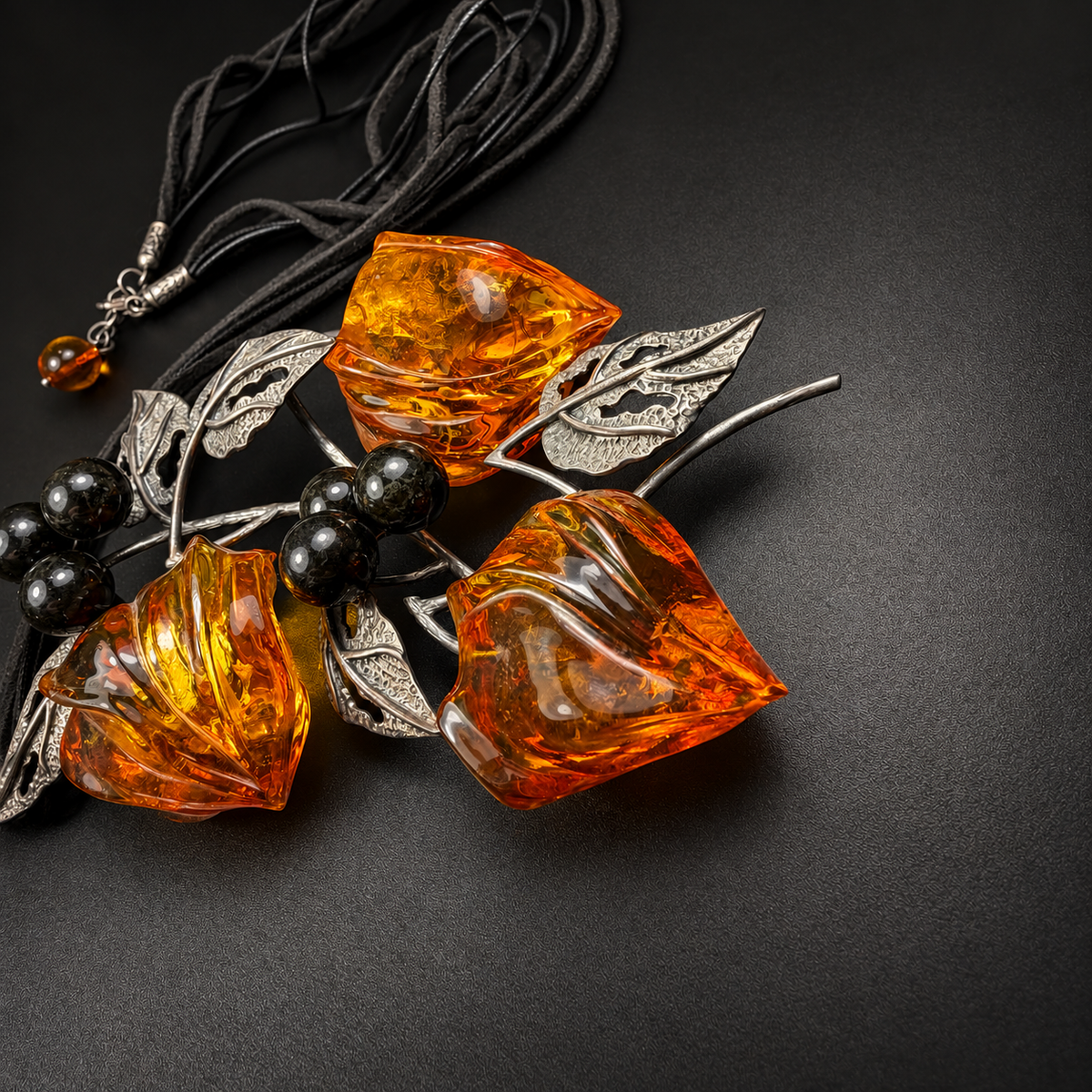 Side detail of carved amber buds and dark berry beads on black, studio view 6