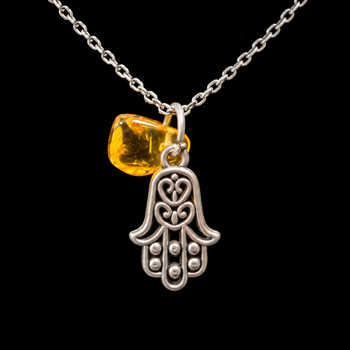 Made in USA Natural Baltic Amber Hamsa necklace by KIZIMA®, openwork metal protective hand with golden amber on a fine chain, black background