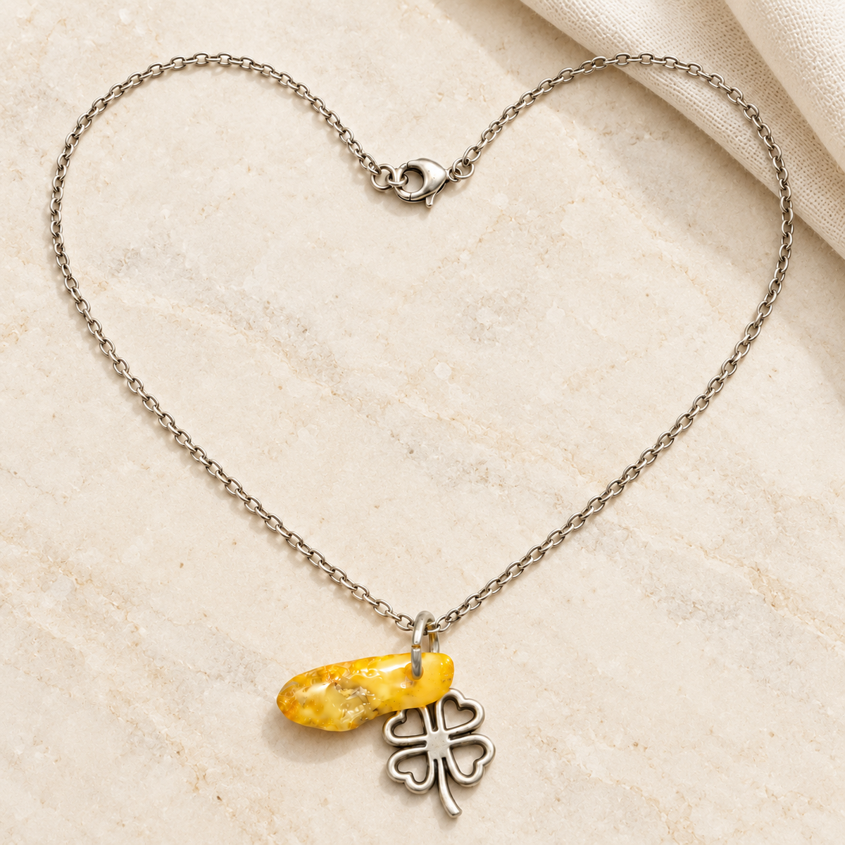 Made in USA Natural Baltic Amber clover necklace by KIZIMA® with fine metal chain arranged on a neutral tabletop