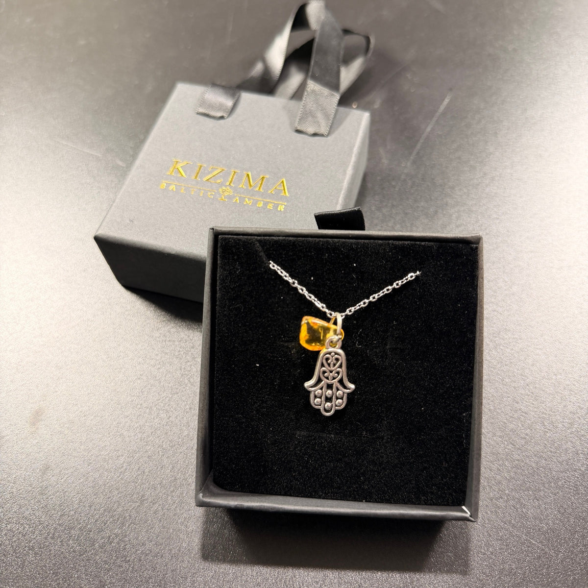 Made in USA Natural Baltic Amber Hamsa necklace by KIZIMA® displayed in a gray KIZIMA® gift box with black insert