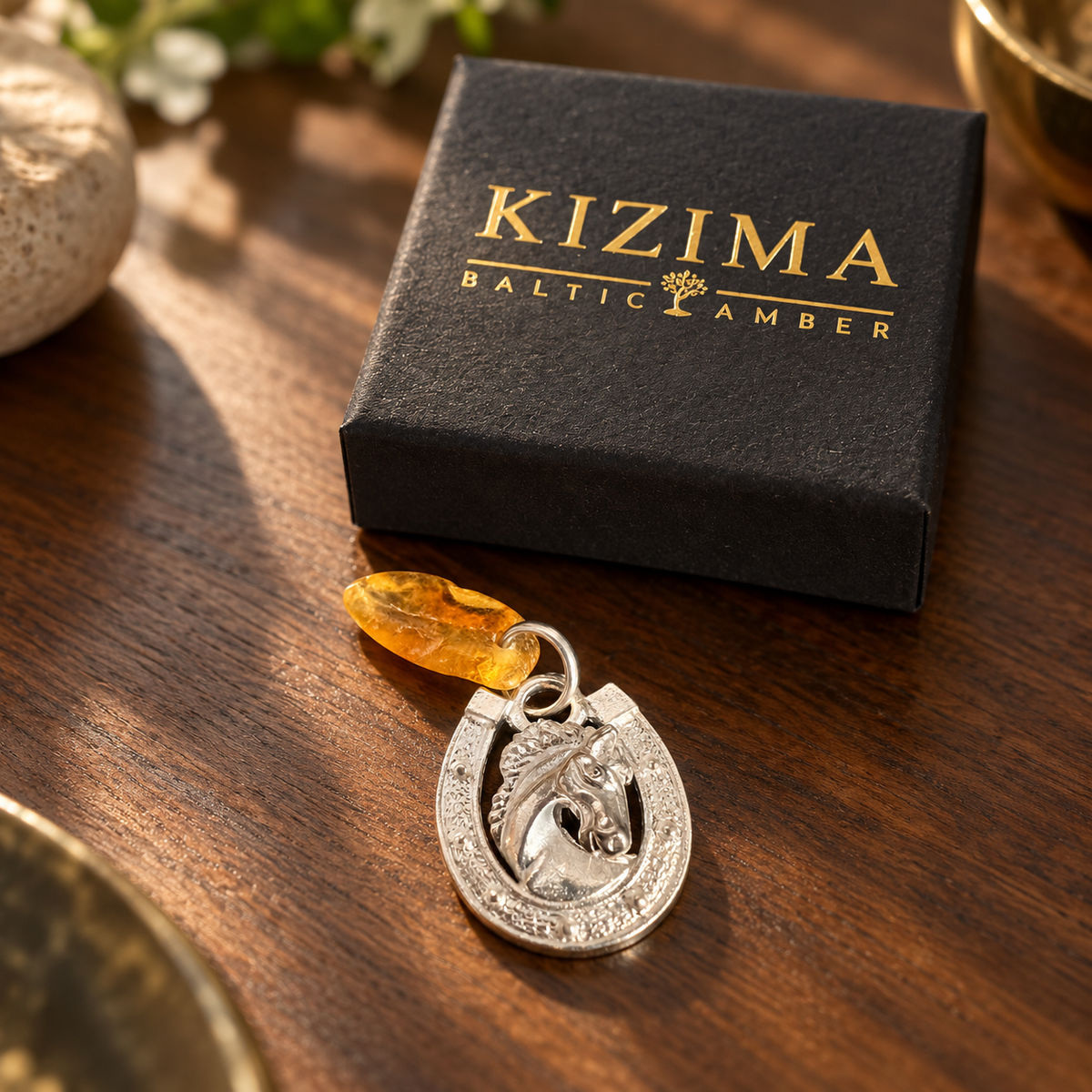 KIZIMA horseshoe horse head amulet with golden amber and its gift box in a warm home tabletop setting