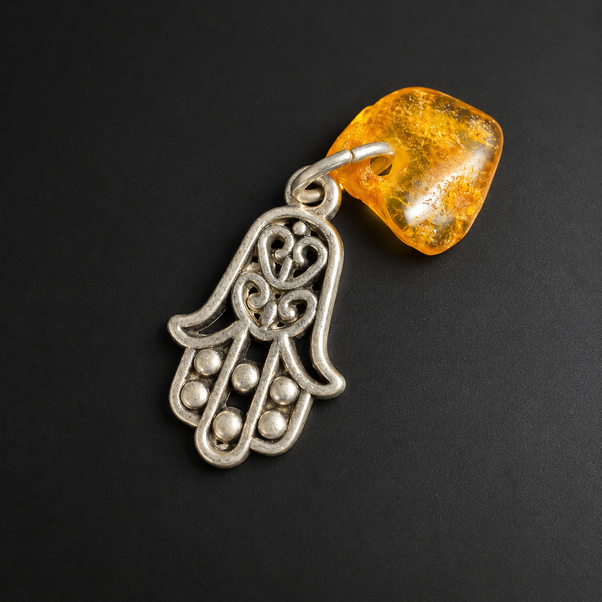 Made in USA Natural Baltic Amber Hamsa amulet by KIZIMA®, silver-tone openwork hand linked to an irregular honey amber piece on black