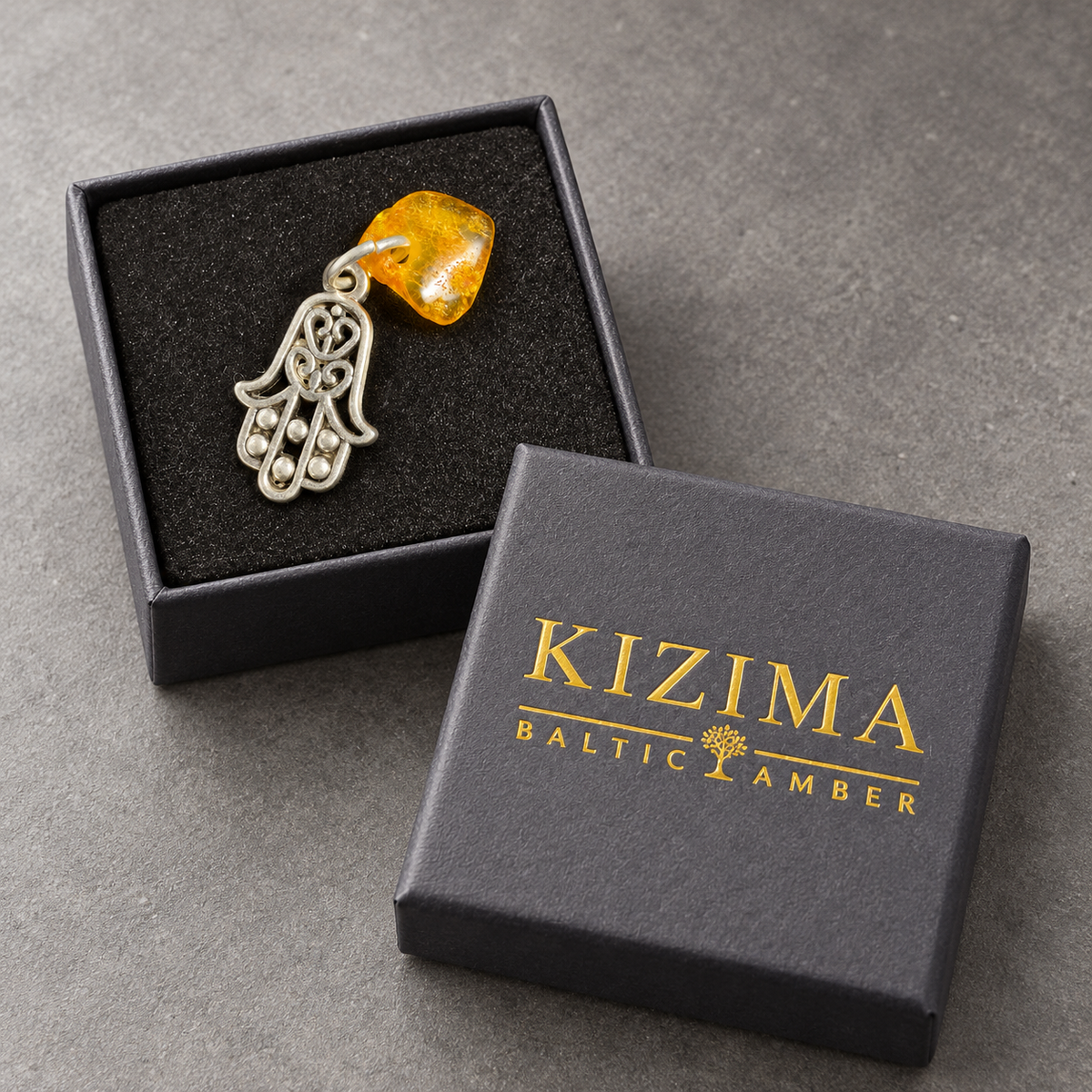 Made in USA Natural Baltic Amber Hamsa amulet by KIZIMA® in black foam inside the gray KIZIMA® gift box with gold lettering