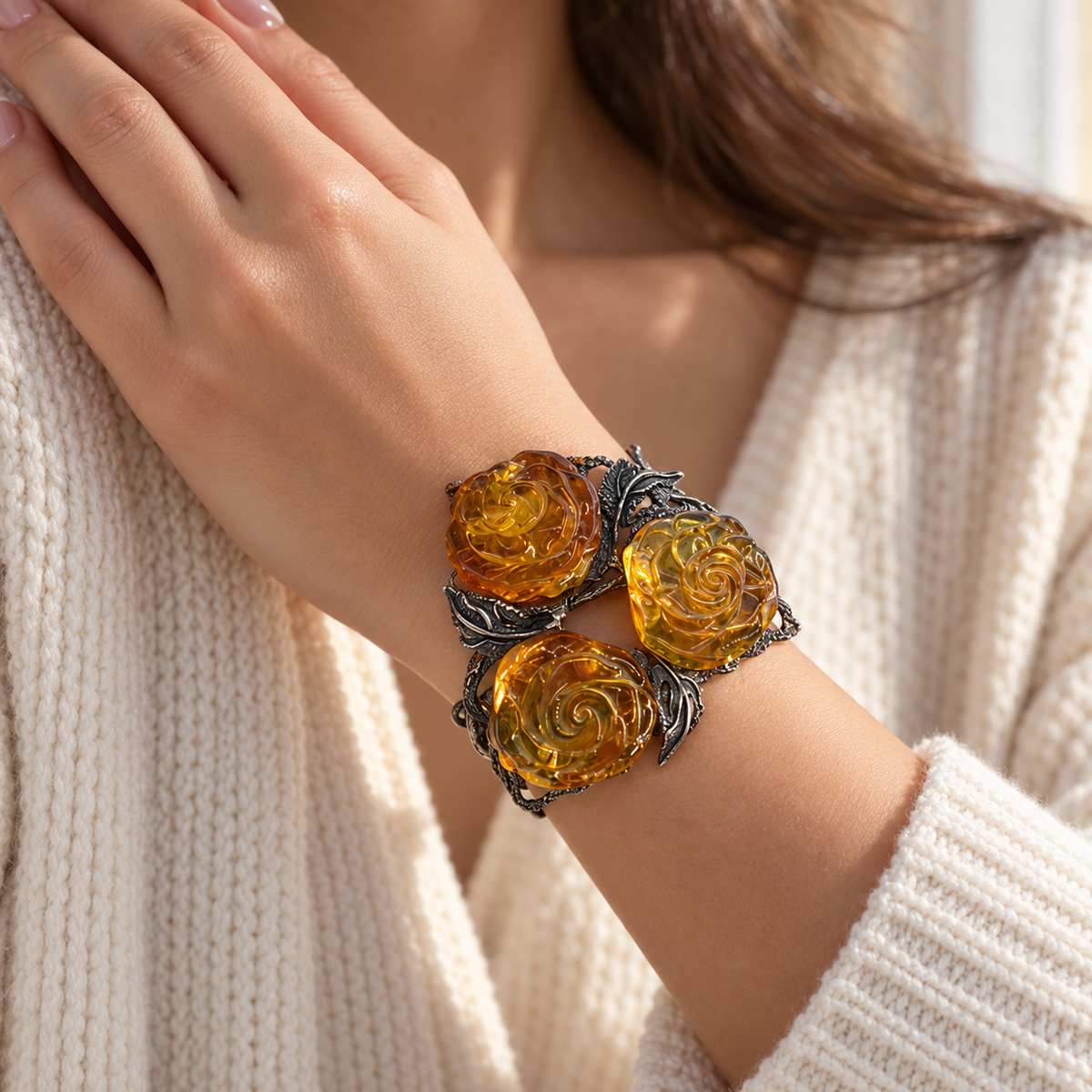 KIZIMA 3E30000q67.1 cuff with three carved honey amber roses and silver-tone leaves worn on a woman's wrist