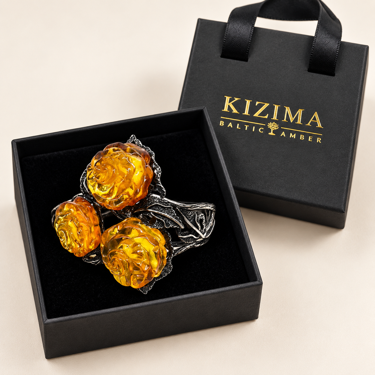KIZIMA 3E30000q67.1 cuff with three carved honey amber roses and silver-tone leaves on clean black velvet in its KIZIMA gift box