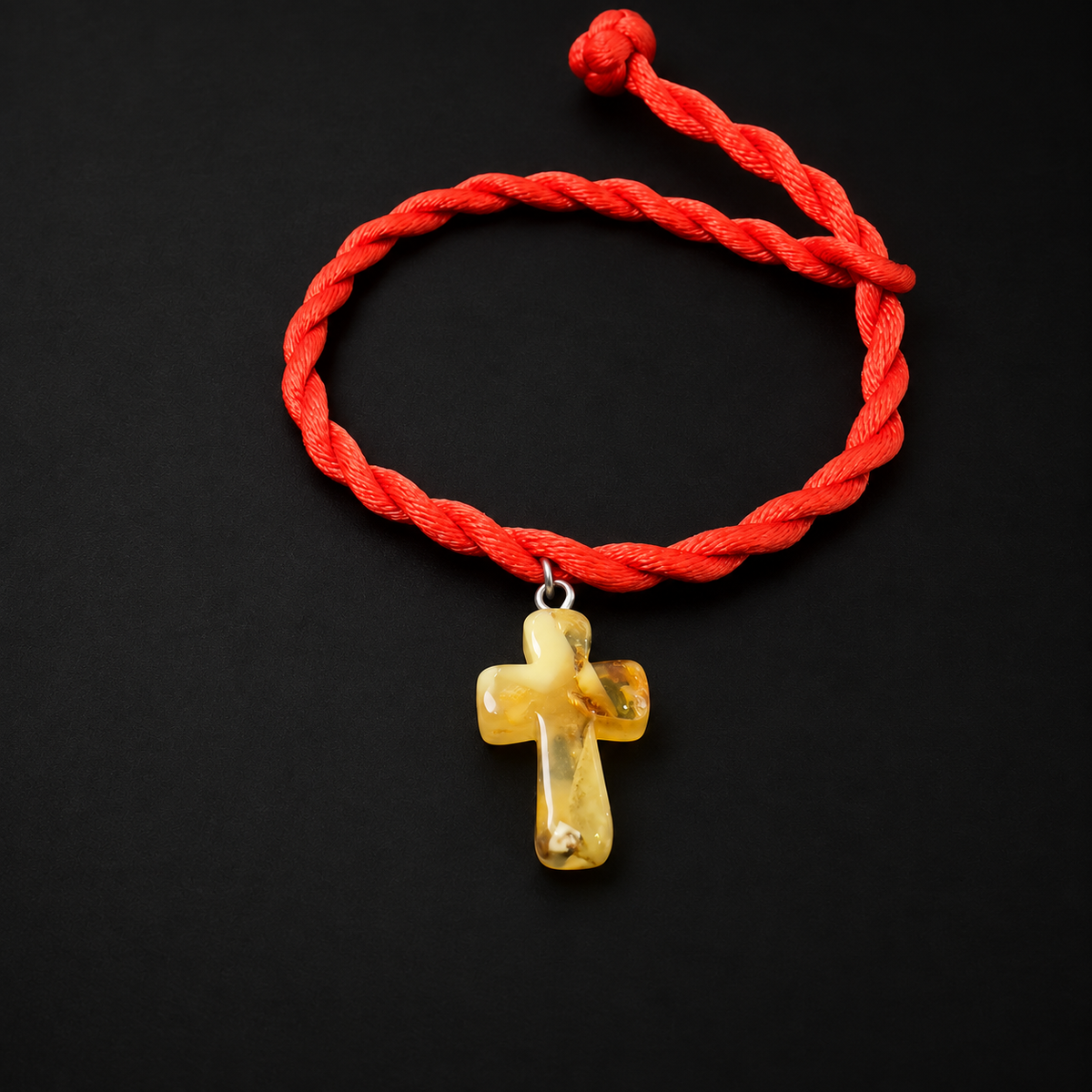 KIZIMA yellow amber cross pendant on red twisted rope bracelet in a black studio
