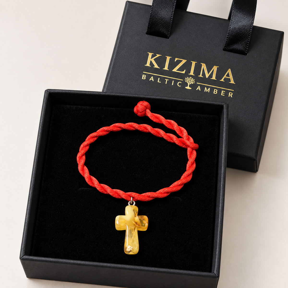 KIZIMA yellow amber cross pendant on red twisted rope bracelet inside a black KIZIMA gift box