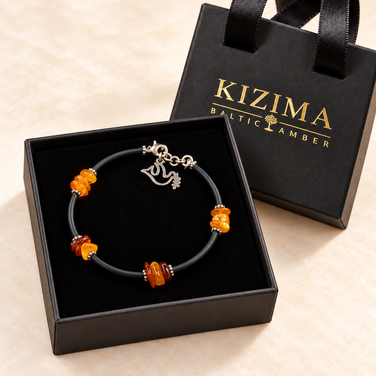 KIZIMA 3G0075q5 amber chip bracelet with black cord and silver dove charm in its KIZIMA gift box on clean black velvet
