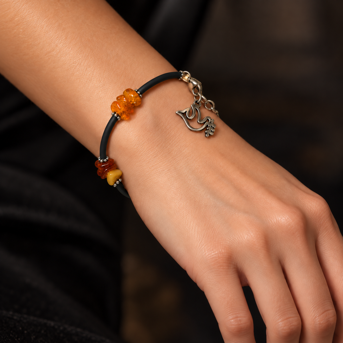 KIZIMA 3G0075q5 amber chip bracelet with black cord and silver dove charm worn on a young adult woman's wrist