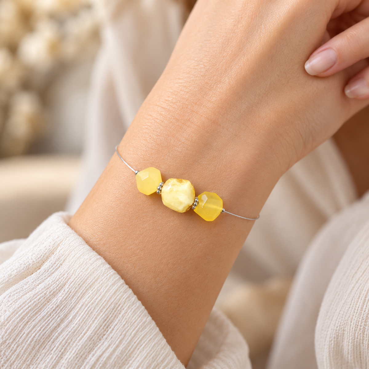 KIZIMA bracelet with three faceted yellow amber stones on a delicate silver-colored cable, worn on a woman's wrist.