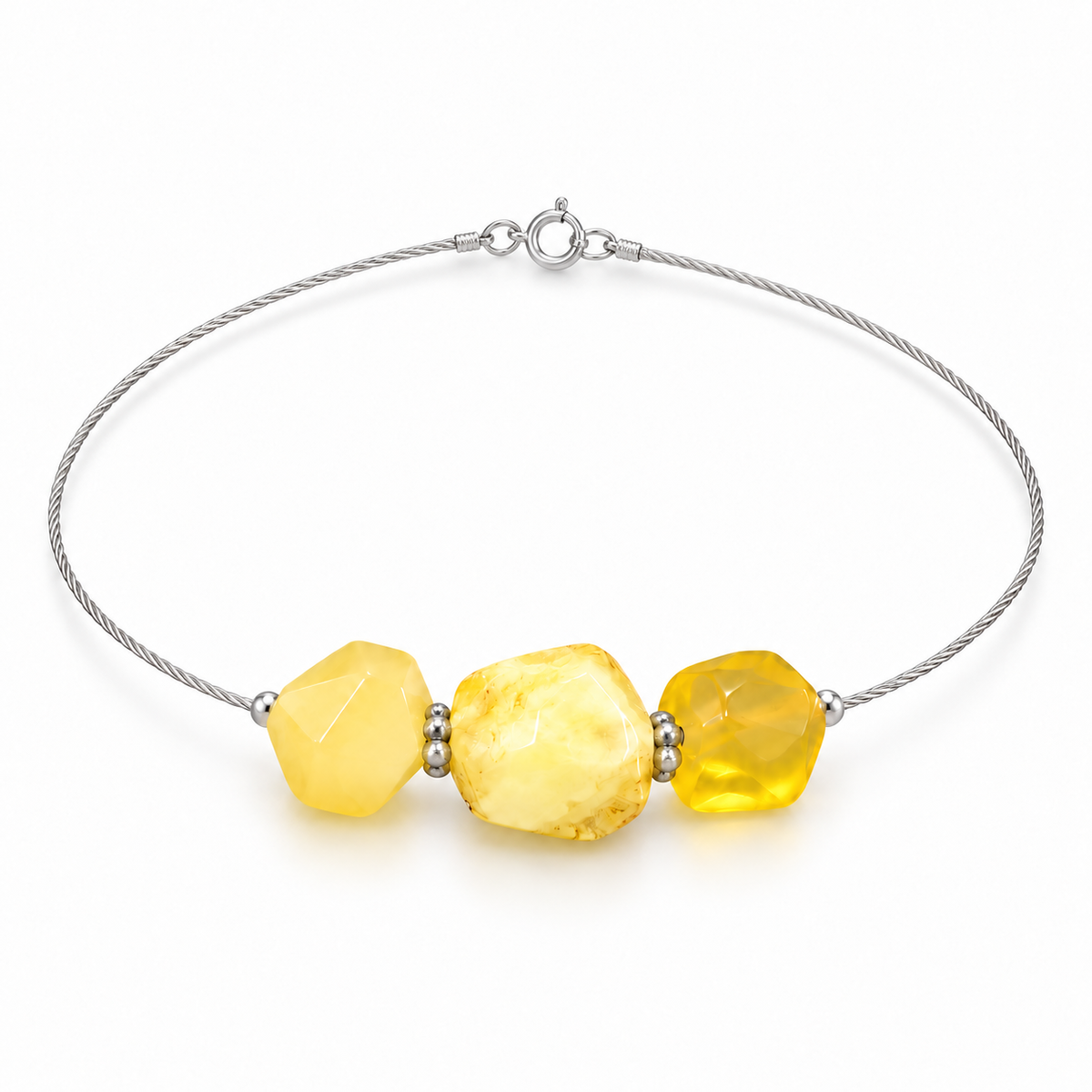 Three faceted yellow amber stones and silver-colored spacers on a fine cable bracelet, isolated on a white background.