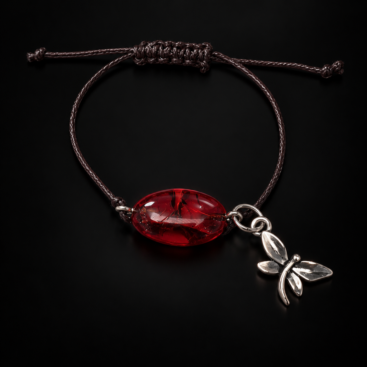 KIZIMA 3G0100q2.69 dark cherry oval amber cord bracelet with silver-tone dragonfly charm on a black studio background