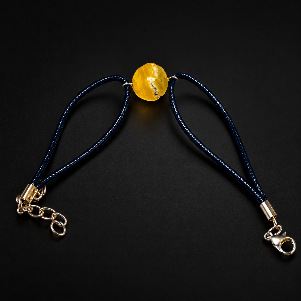 KIZIMA 3G0100q3.47 yellow amber single-stone bracelet on dark navy cord on a black studio background