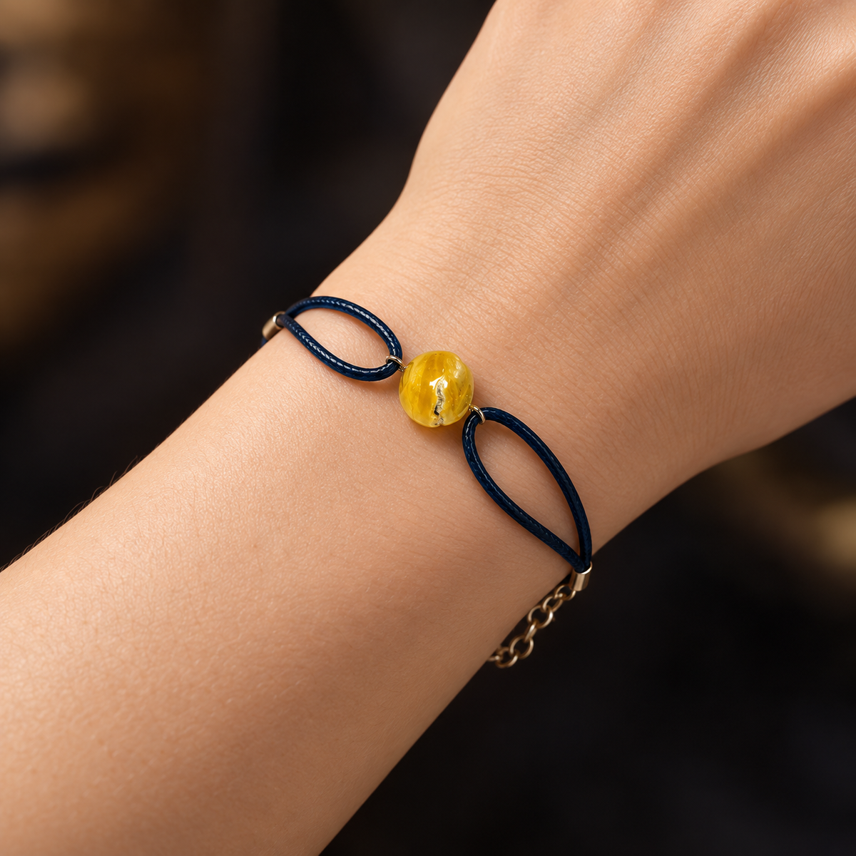 KIZIMA 3G0100q3.47 yellow amber single-stone bracelet on dark navy cord worn on an adult woman's wrist