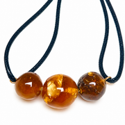 KIZIMA 3G0100q5.53 three cognac and honey amber beads on doubled black cord, white-background front detail with closure outside frame