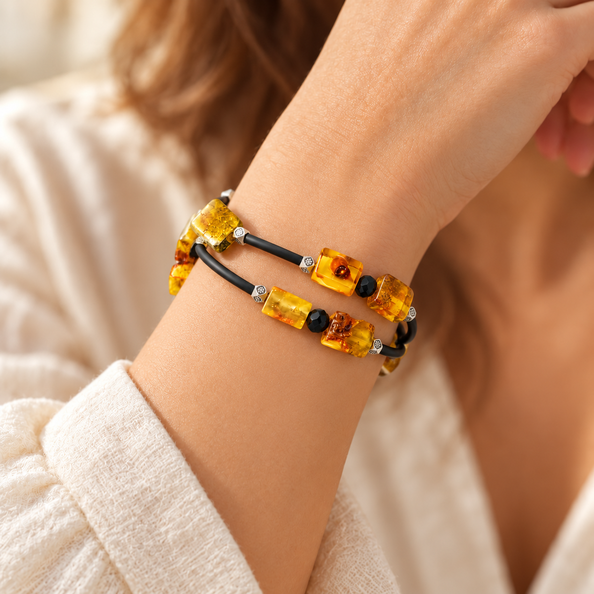 Yellow amber and black spiral bracelet wrapped around a woman's wrist with silver-tone cube accents