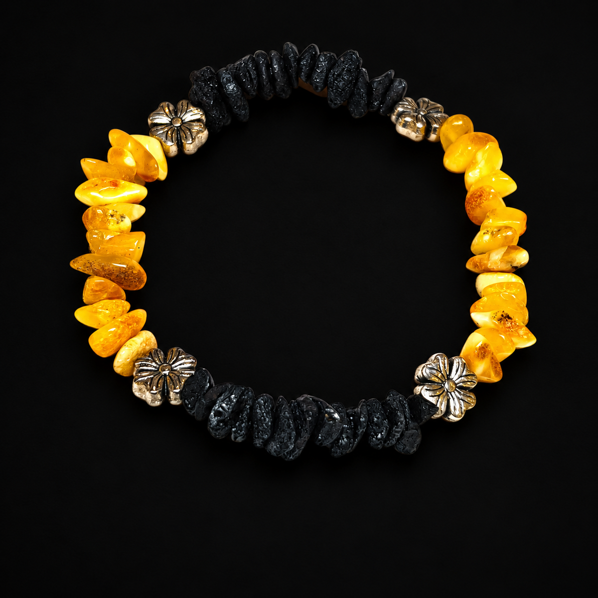 Yellow and black amber chip bracelet with four silver-tone flower spacers by KIZIMA in a black studio setting.